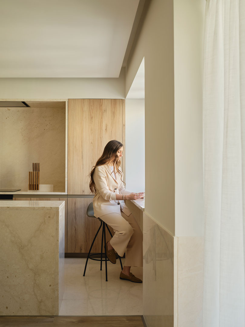 Persona sentada en la cocina del apartamento Calasanz junto al zócalo de piedra