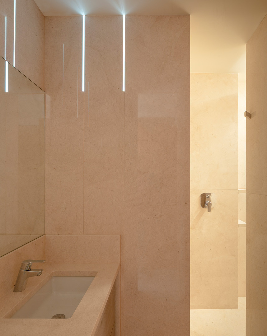 Baño del apartamento de piedra con lavabo de piedra y luz entrando por una hendidura