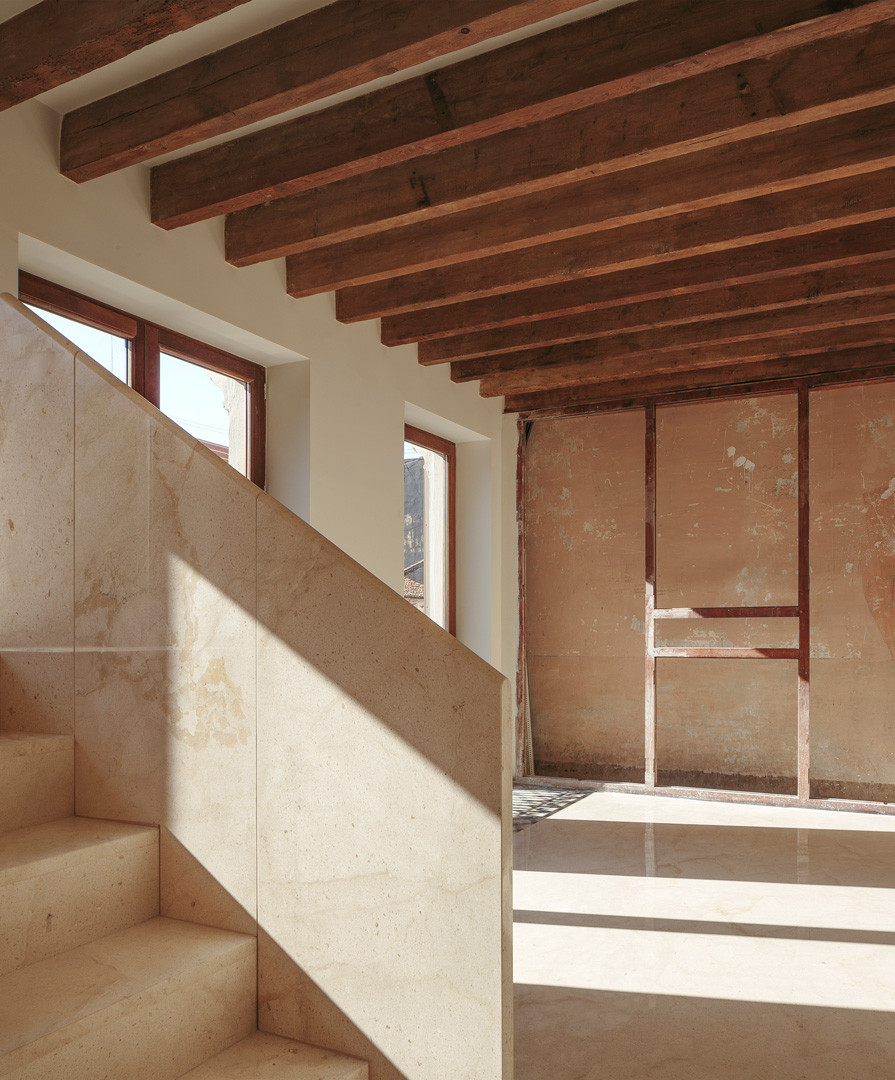 Escalera de piedra bajo el techo de viguetas de madera, frente a un muro original conservado en la Casa de los Gigantes