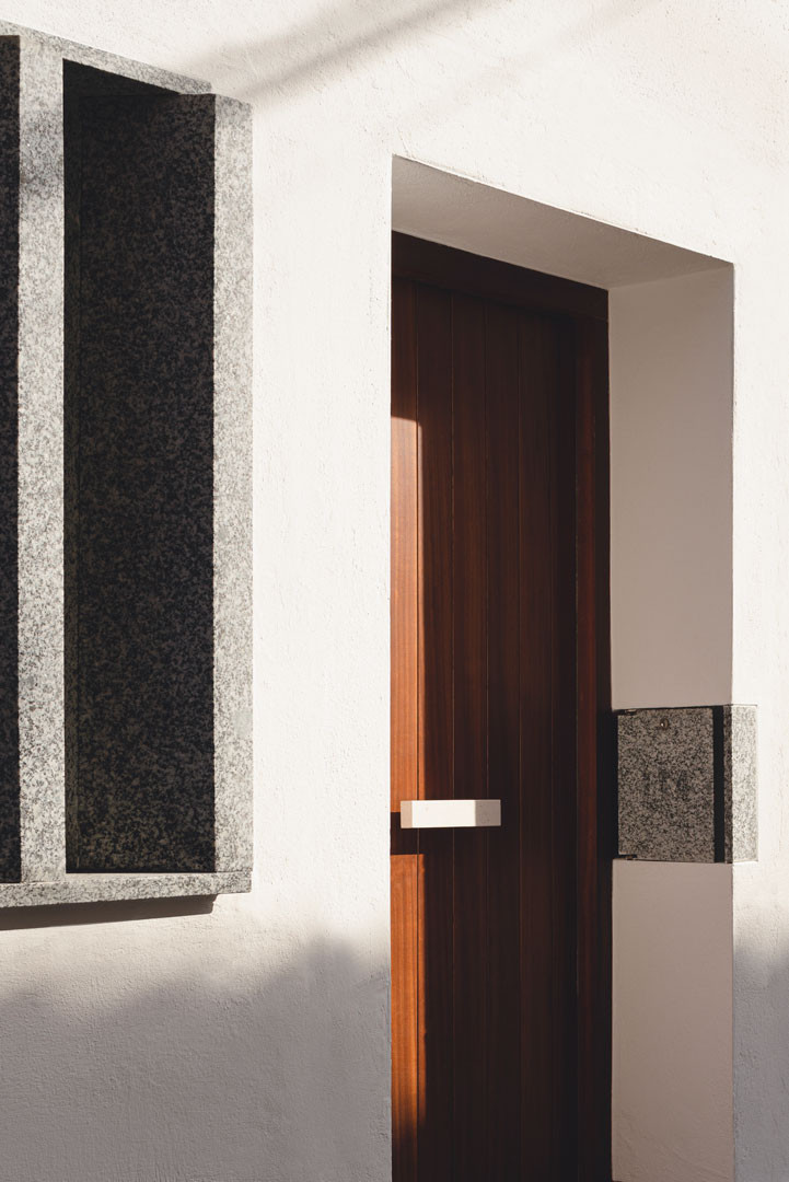 Entrada de Casa Mirasol con puerta de madera, celosía y buzón de granito