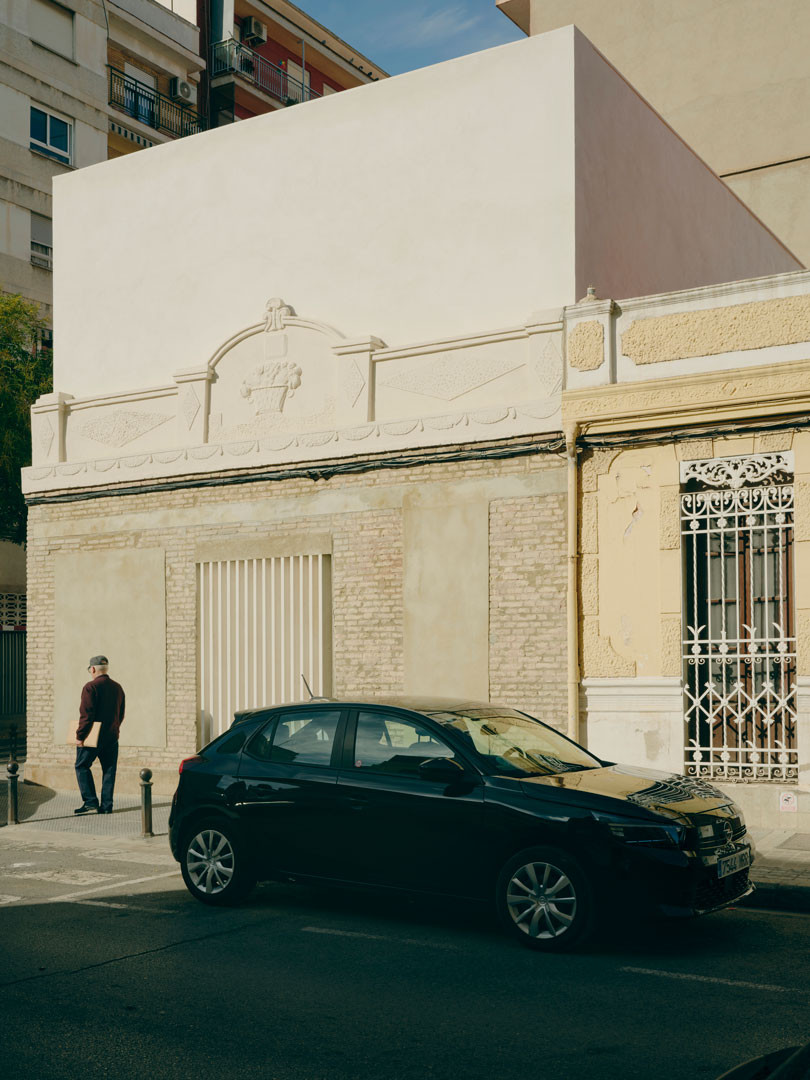 Fachada original con friso de Casa Nido en Torrefiel, Valencia, con el nuevo volumen blanco asomando por detrás