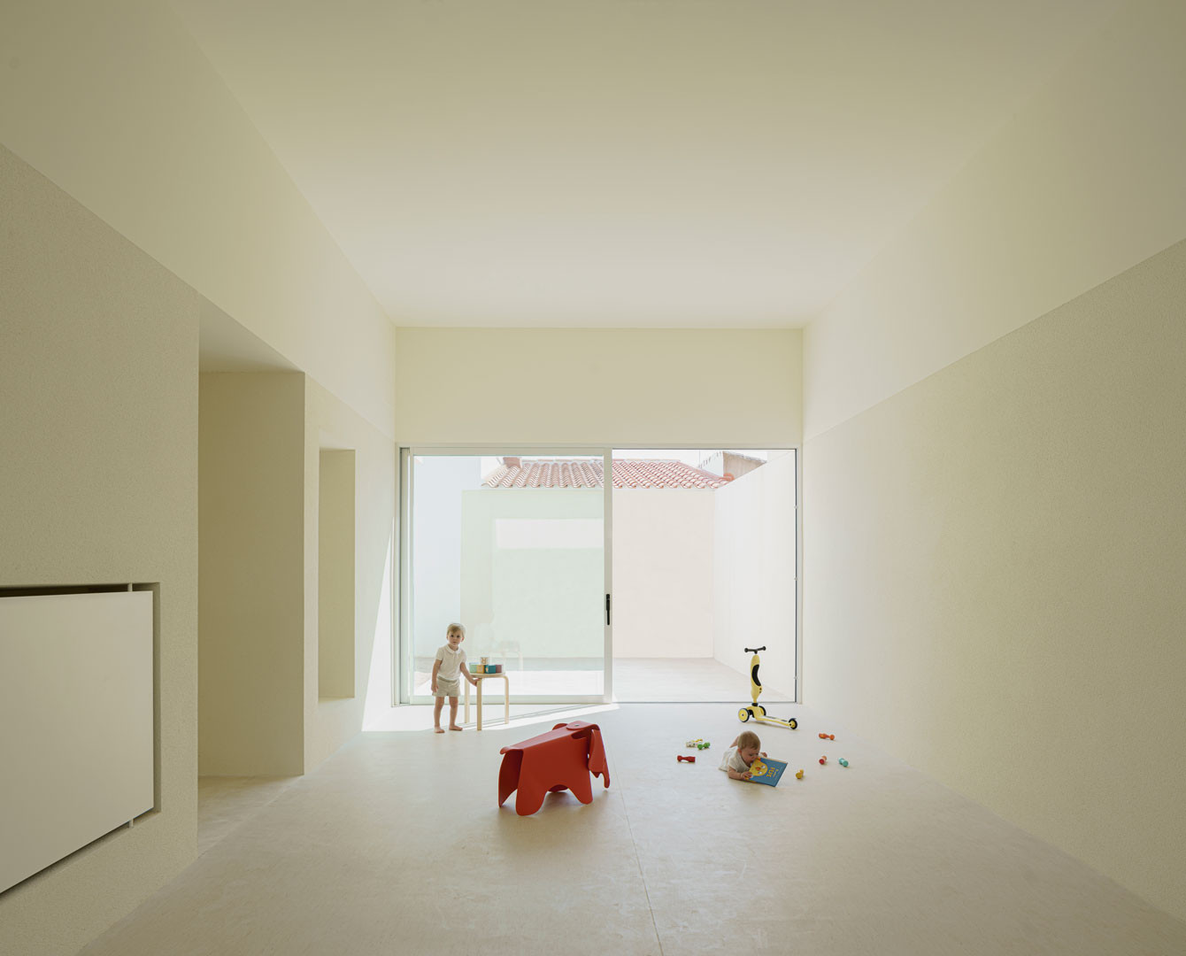 Sala de gran altura entre dos patios de la Escuela en Aguas Nuevas, con niños al fondo