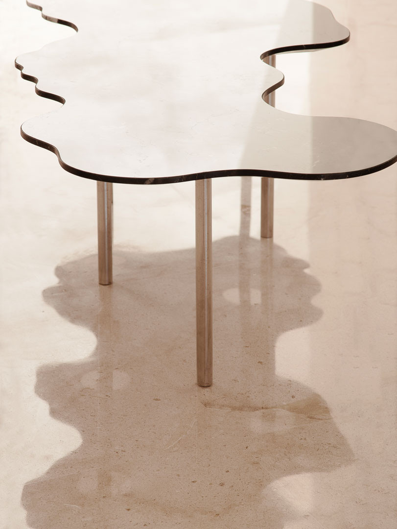 Lago table seen at an angle, with its curves and the shadow cast on the floor