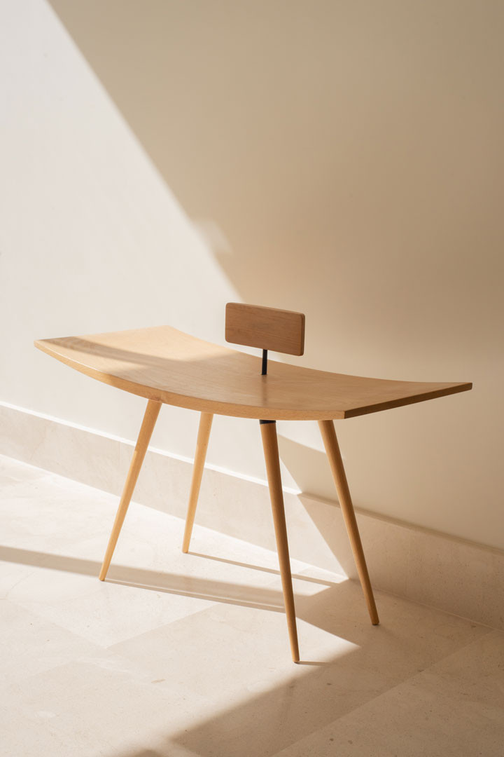 Silla Moji en madera maciza curvada, con respaldo de tablero y patas finas, vista en tres cuartos