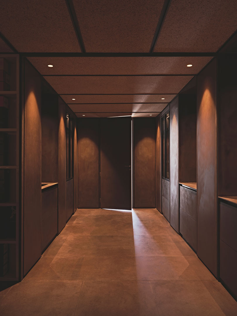 Narrow threshold flanked by steel niches in Tinta
