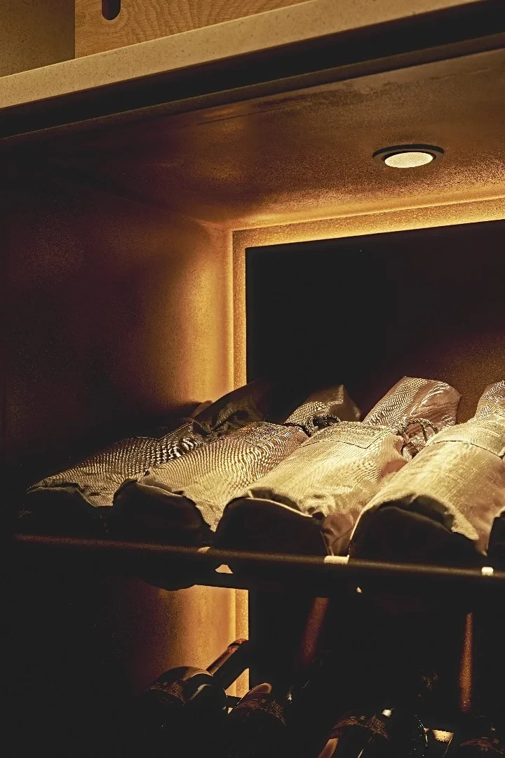 Lit limestone niches holding wine bottles in Tinta